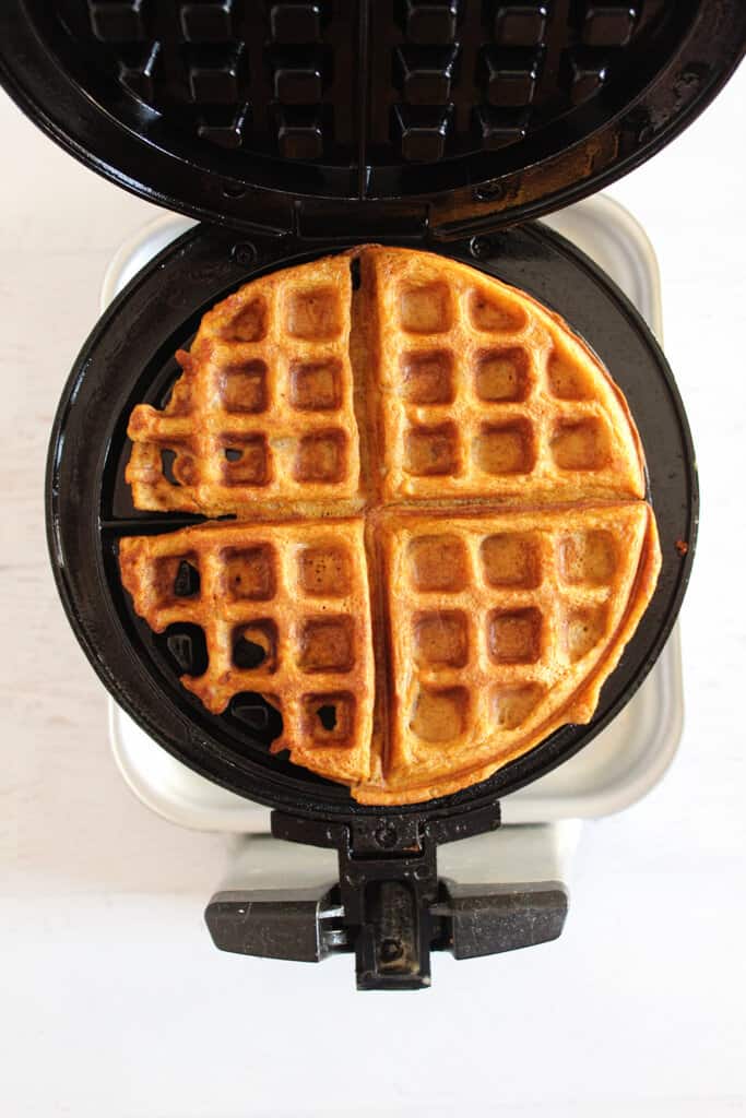 pumpkin waffles cooking in a waffle iron.