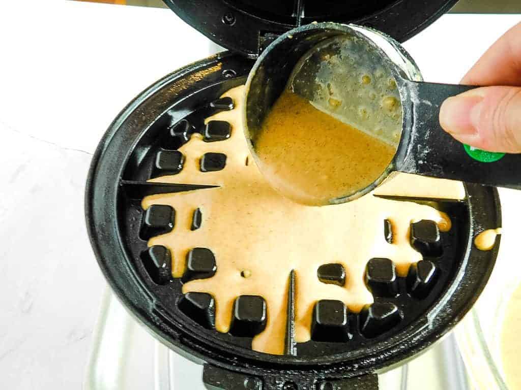 gluten free pumpkin waffle batter being poured into a waffle iron