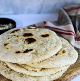 Stack of gluten free pita bread on a wooden cutting board