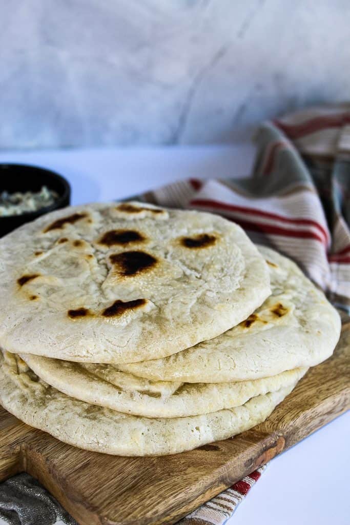 Stack of gluten free pita bread on a wooden cutting board