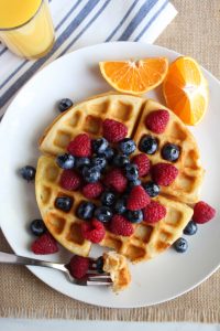 gluten free belgian waffles on a white plate with fruit