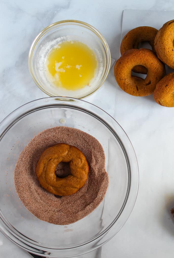 gluten free pumpkin donuts dipped in sugar in a glass bowl