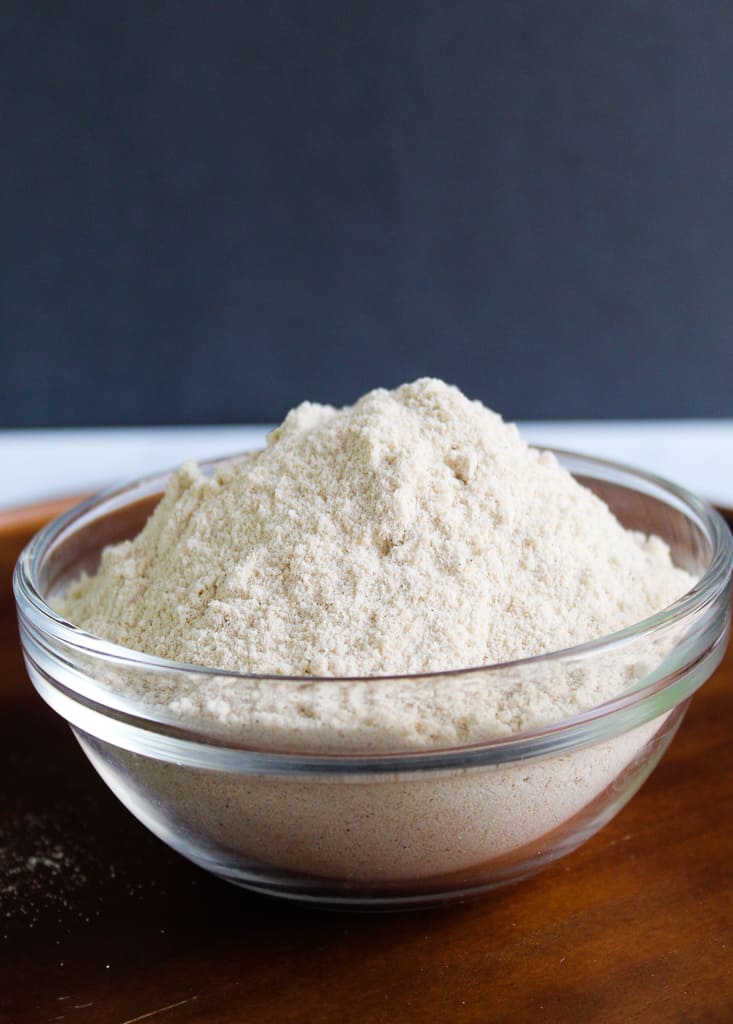 bowl of sorghum flour sitting on a wooden cutting board.