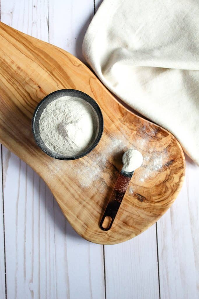 aardappelmeel in een lepel zittend op een houten snijplank.