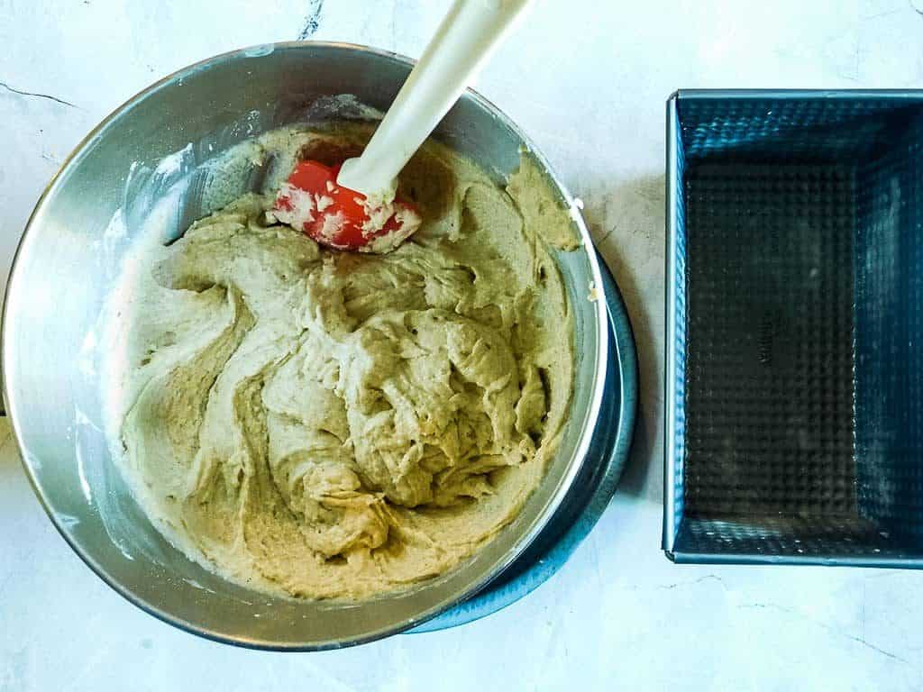 gluten free vegan bread batter in a bowl with a black pan nearby