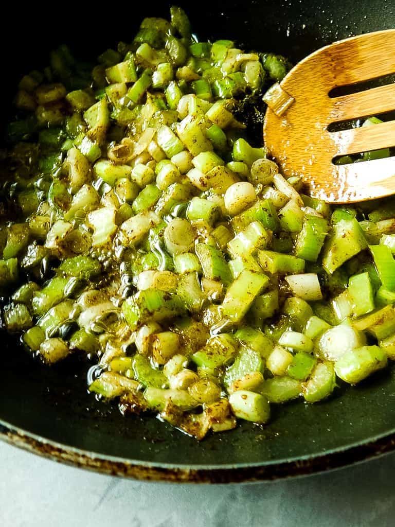 celery and onions sauteed in a black pan