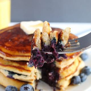 gluten free blueberry pancakes stacked on a white plate