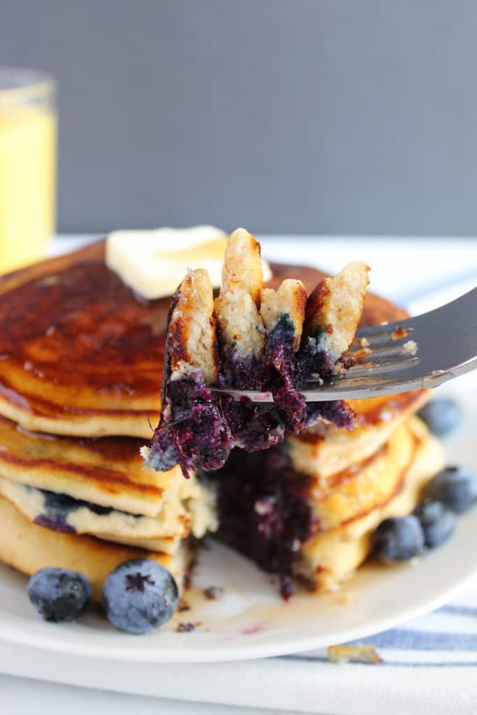 gluten free blueberry pancakes stacked on a white plate