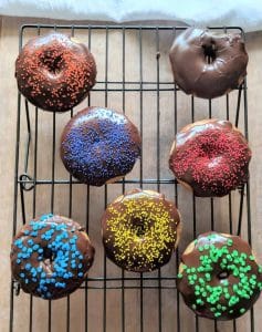 gluten free cake donuts baked with chocolate glaze sitting on a rack.