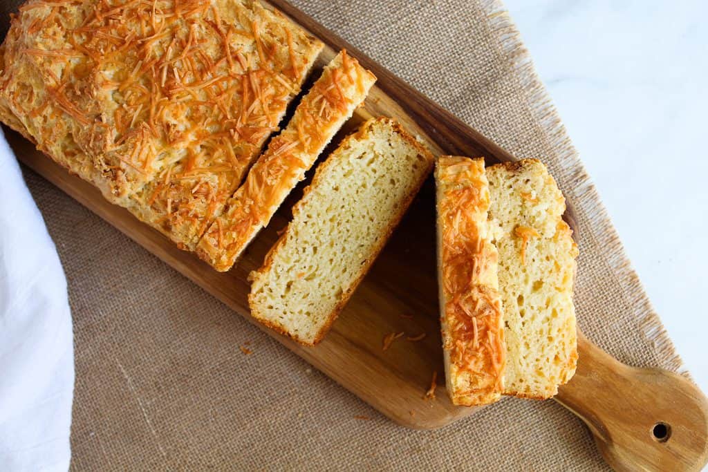 sliced loaf of gluten free garlic bread on a wooden cutting board