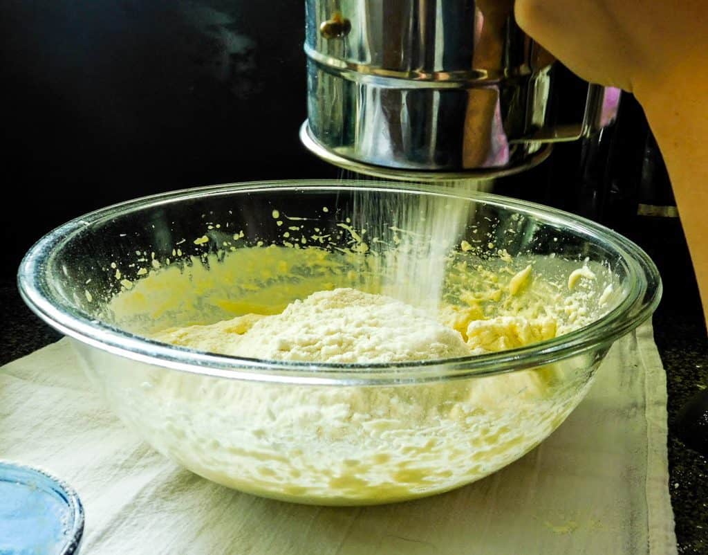 sifting ingredients for low carb bread into a glass bowl.