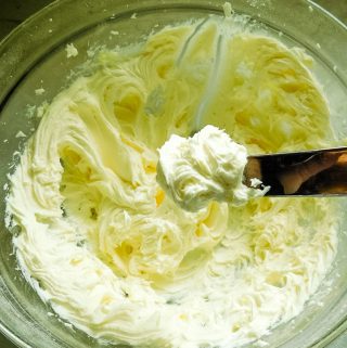 frosting on a metal spatula in a glass bowl