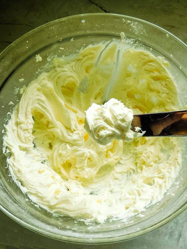 frosting on a metal spatula in a glass bowl