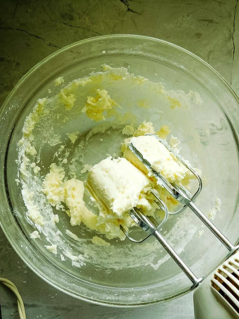 fully mixed frosting on the beaters in a glass bowl