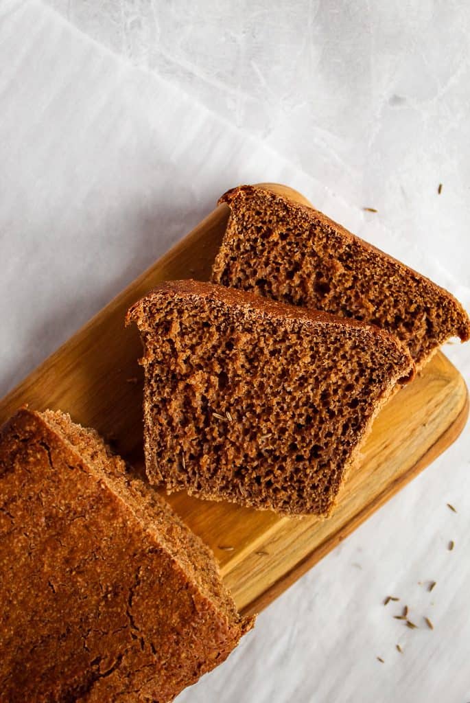 Gluten free pumpernickel bread slices on a wooden cutting board