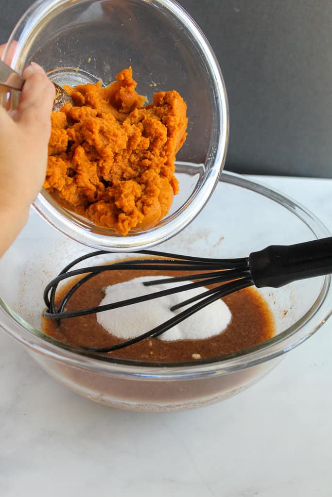 adding pumpkin to gluten free pumpkin donuts batter.