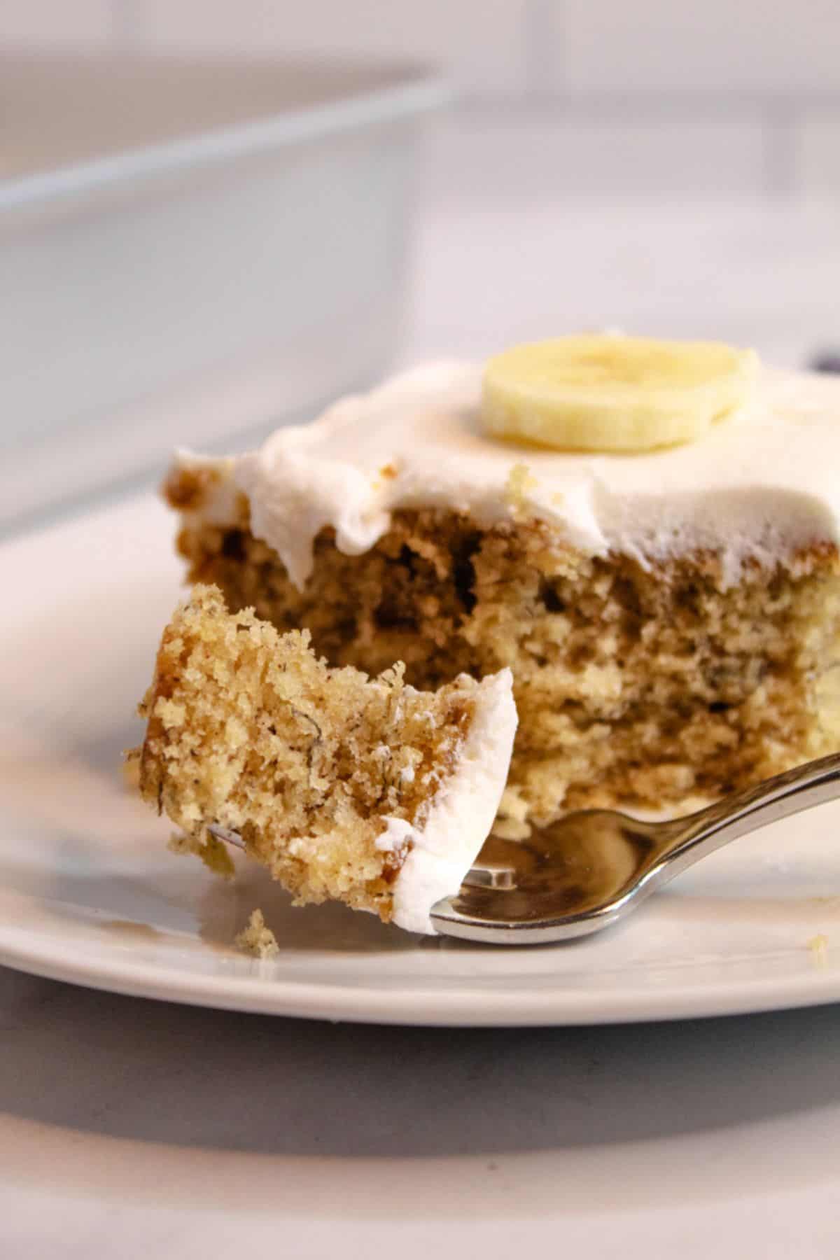 bite of gluten free banana cake on a white plate.