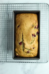baked loaf of gluten free cranberry orange bread on a wire rack
