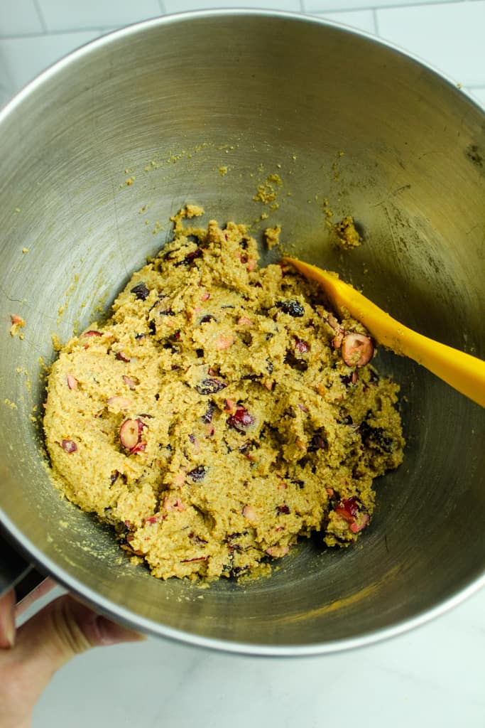 cranberry cookie dough in stainless steel bowl with spoon for mixing