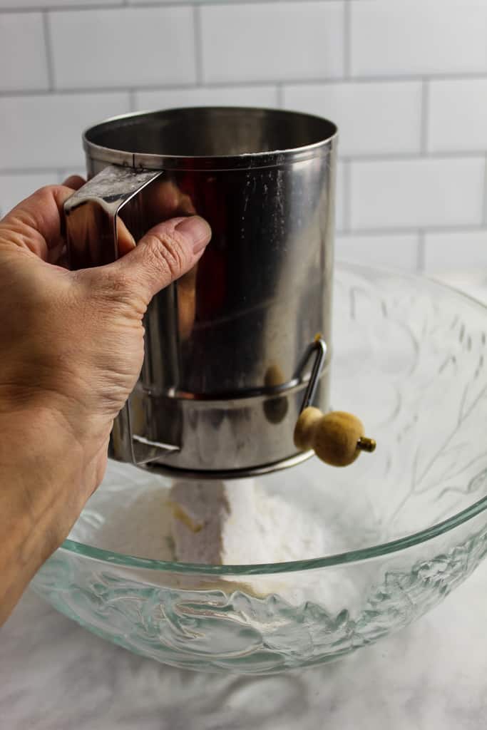 sifting powdered sugar over a bowl