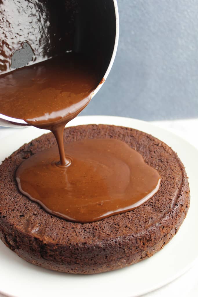 pouring dairy free chocolate ganache on cake