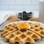 syrup pour onto waffle on a white plate