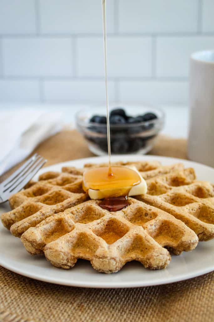 syrup pour onto waffle on a white plate