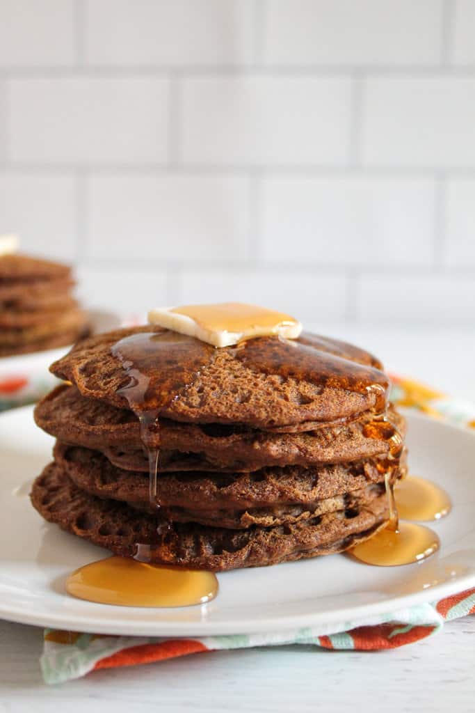 syrup pouring on teff pancakes on a white plate
