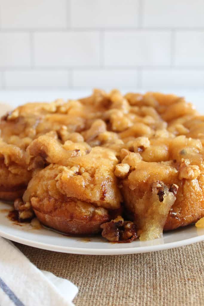 serving sticky buns from a white plate.