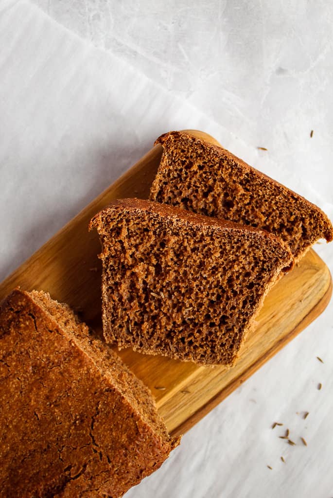 slice of pumpernickel bread on a cutting board.