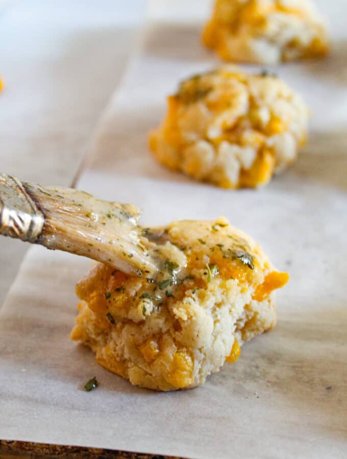 gluten free cheddar bay biscuits with brush of butter on a baking sheet.