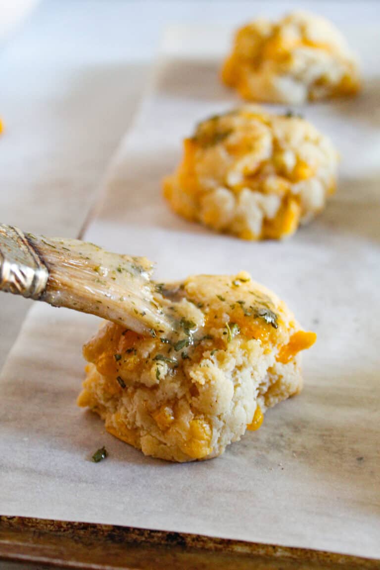 gluten free cheddar bay biscuits with brush of butter on a baking sheet.