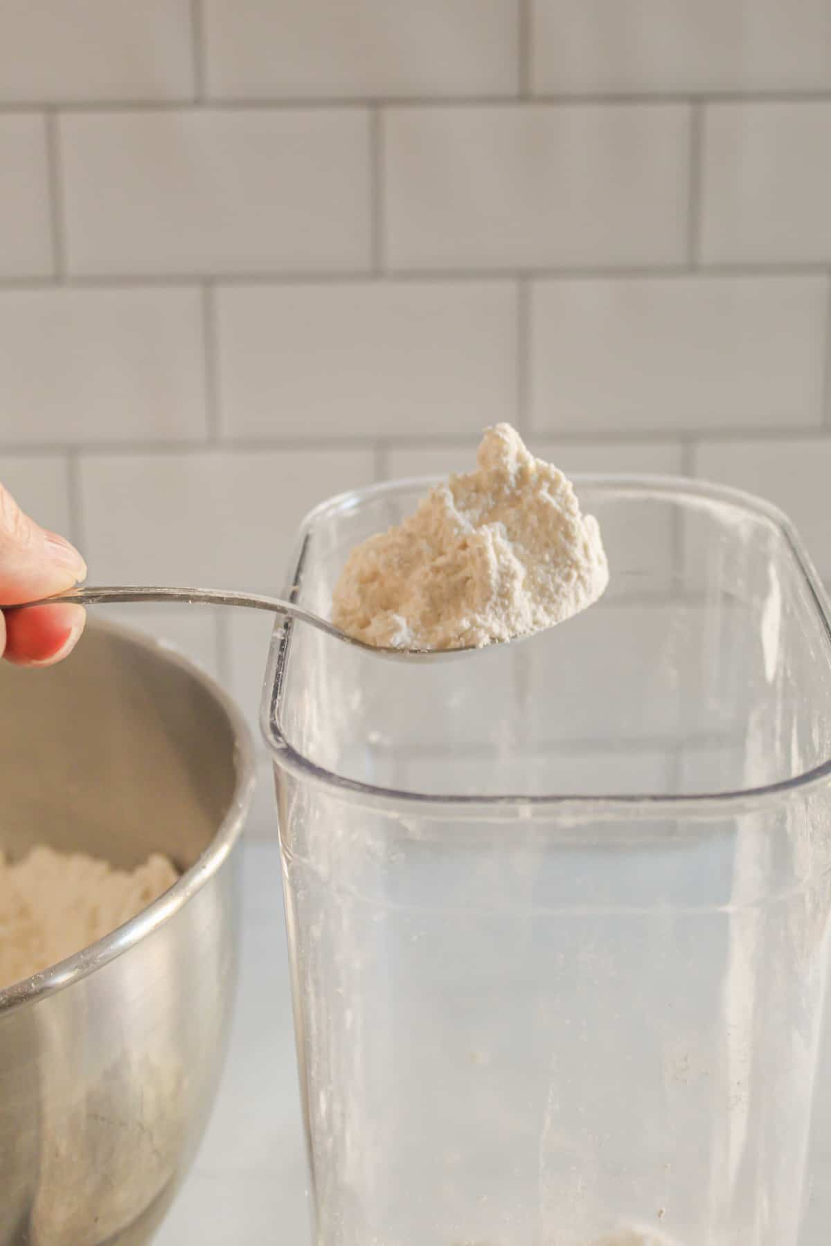 spooning gluten free flour into a container.