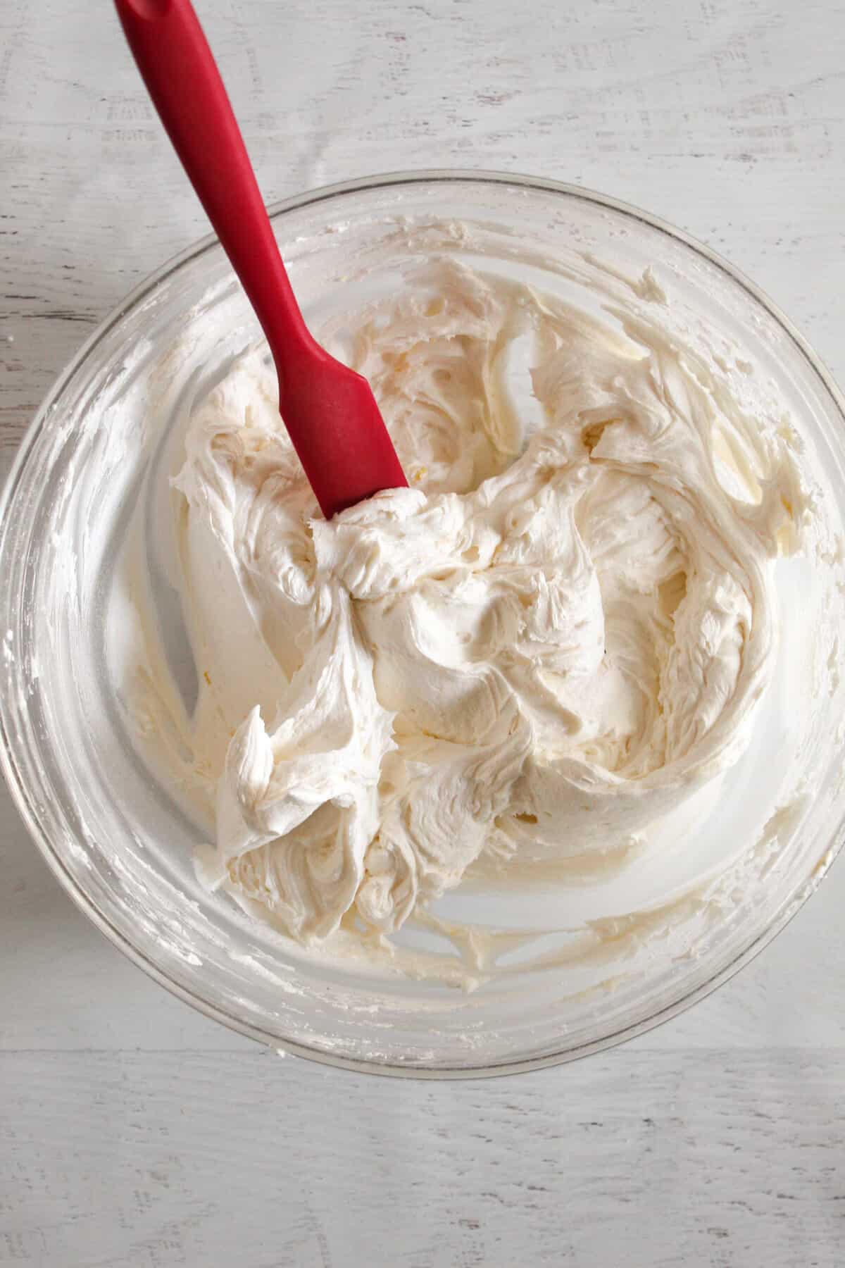 mixing buttercream frosting a bowl.