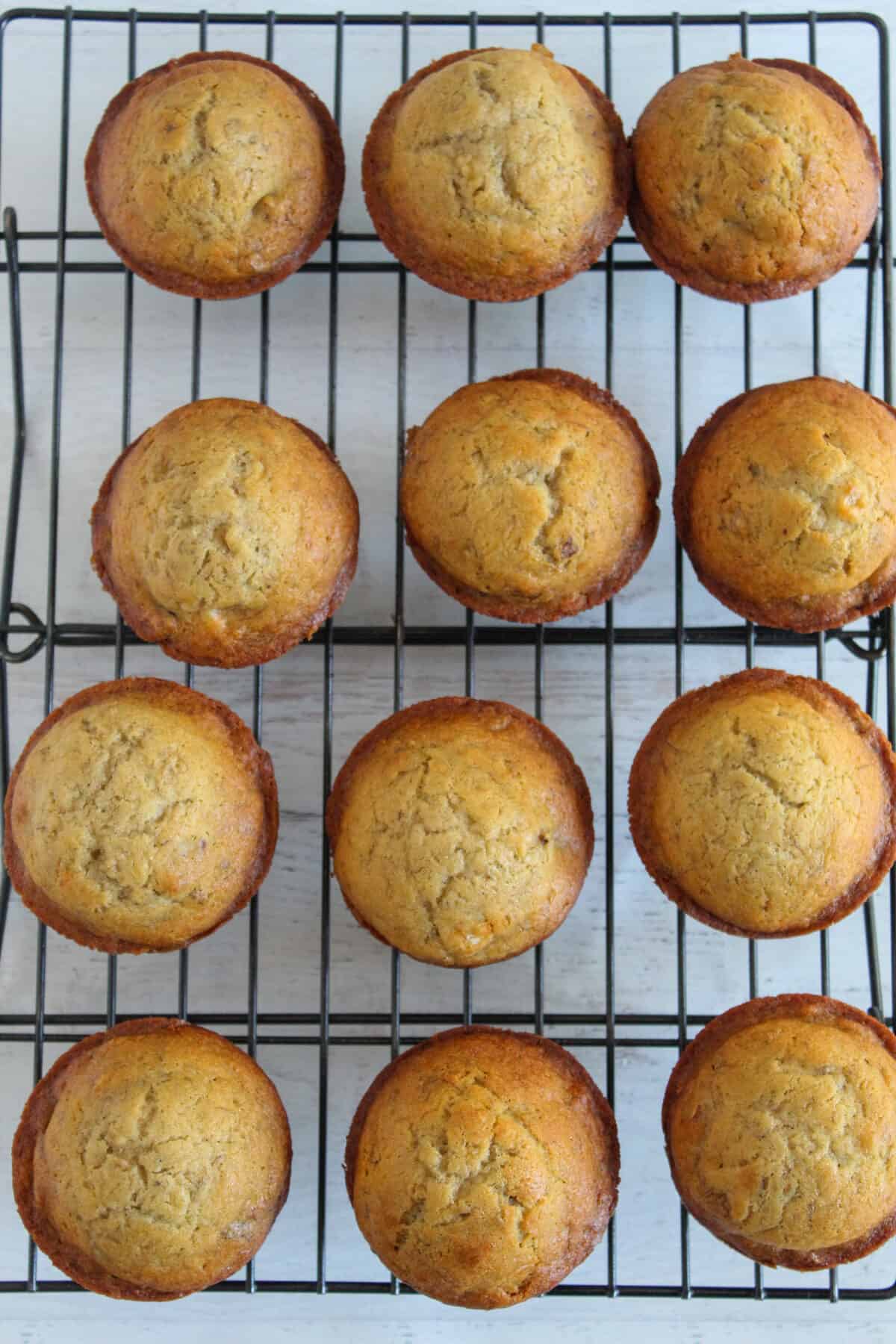 batch of gluten free banana muffins all on a wire rack.