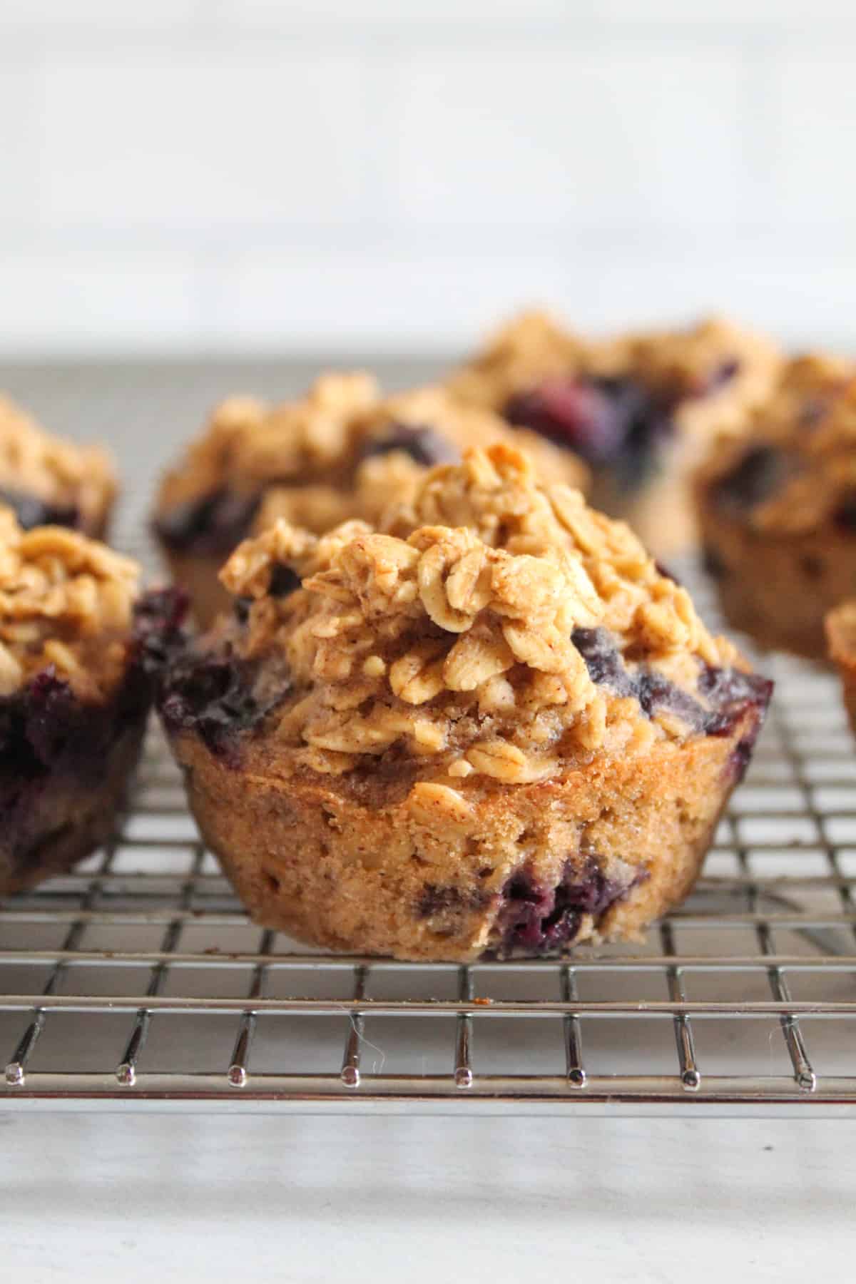 blueberry oatmeal muffin up close, on a wire rack.