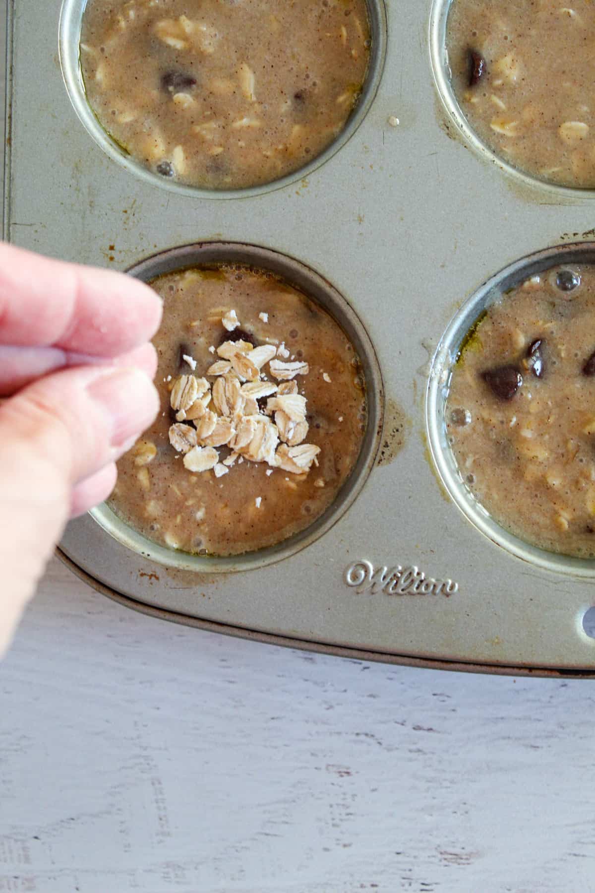 sprinkling oats on top of oatmeal chocolate chip muffins
