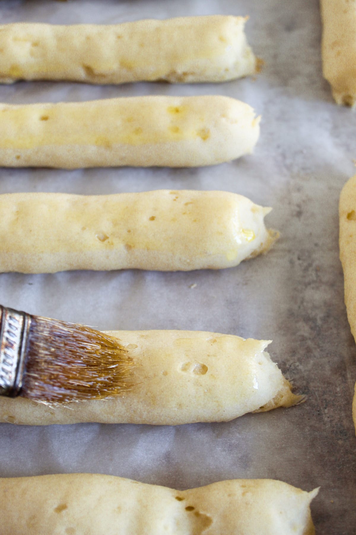 brushing baked breadsticks with olive oil