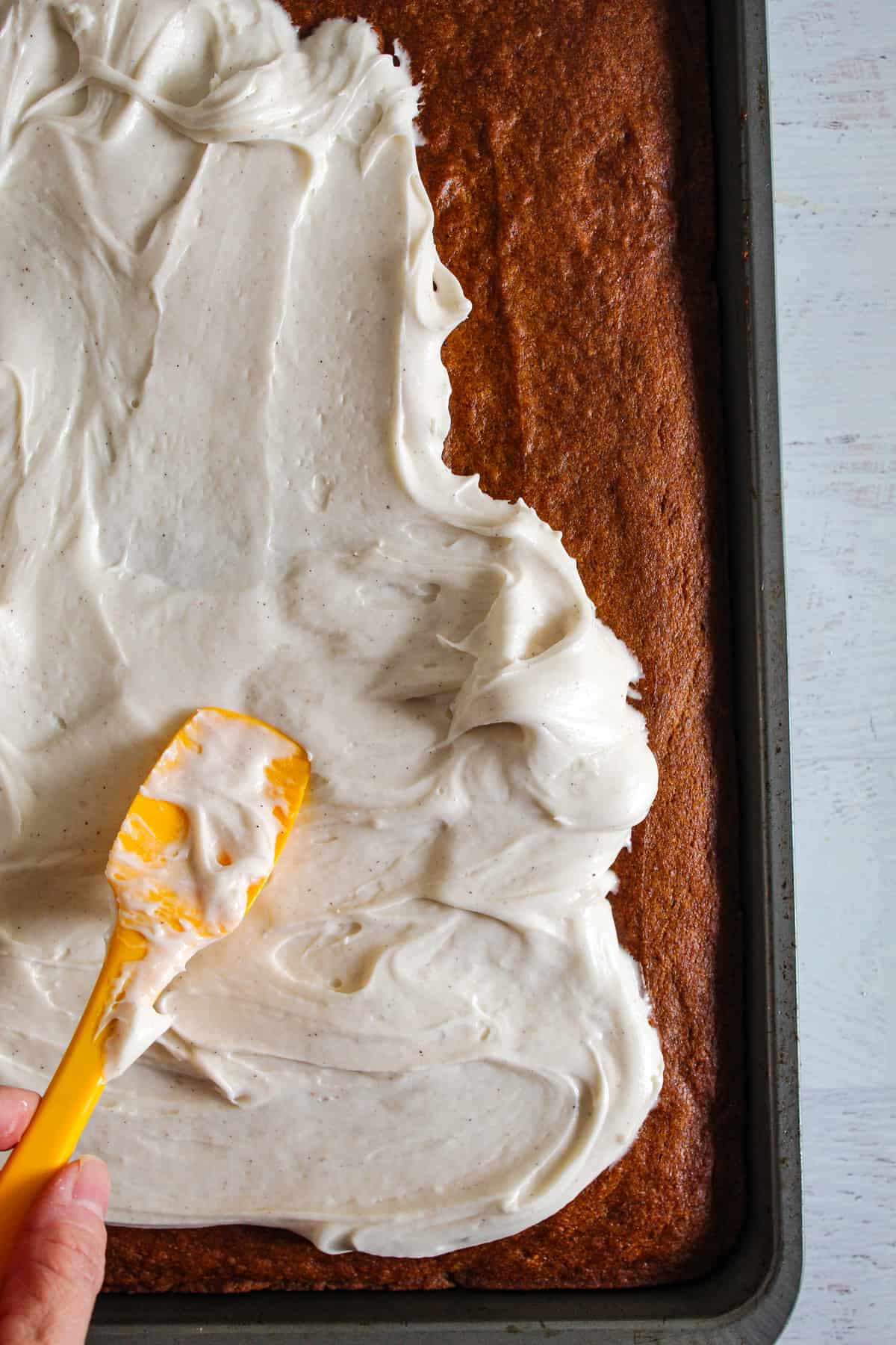 spatula smoothing out cream cheese frosting on pumpkin bars
