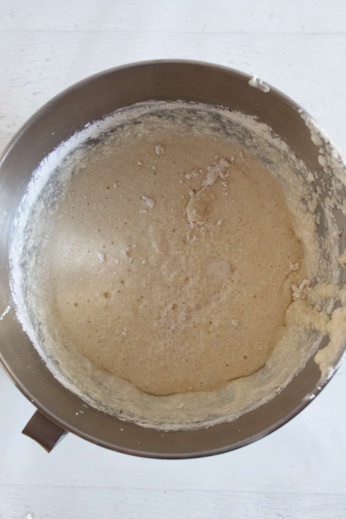 adding buttermilk to cake batter in stainless steel mixing bowl.