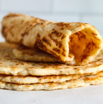 rolled almond flour tortilla sitting on a stack of tortillas