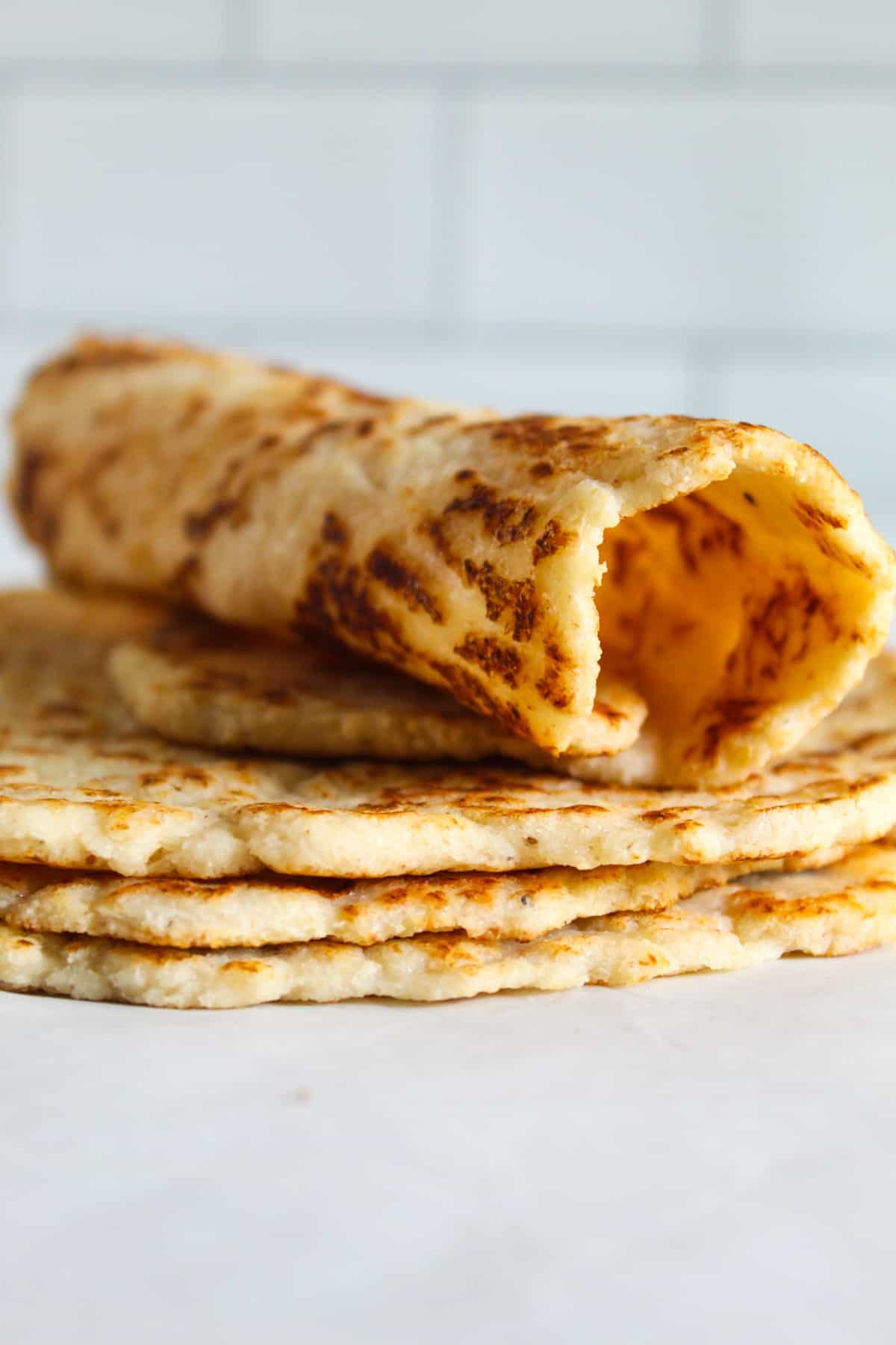 rolled almond flour tortilla sitting on a stack of tortillas