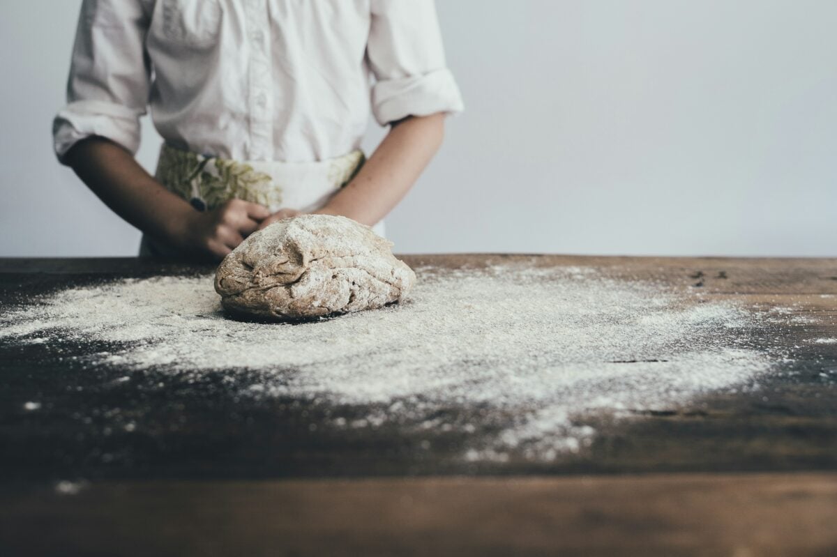 bread dough being kneaded on a floured surface
