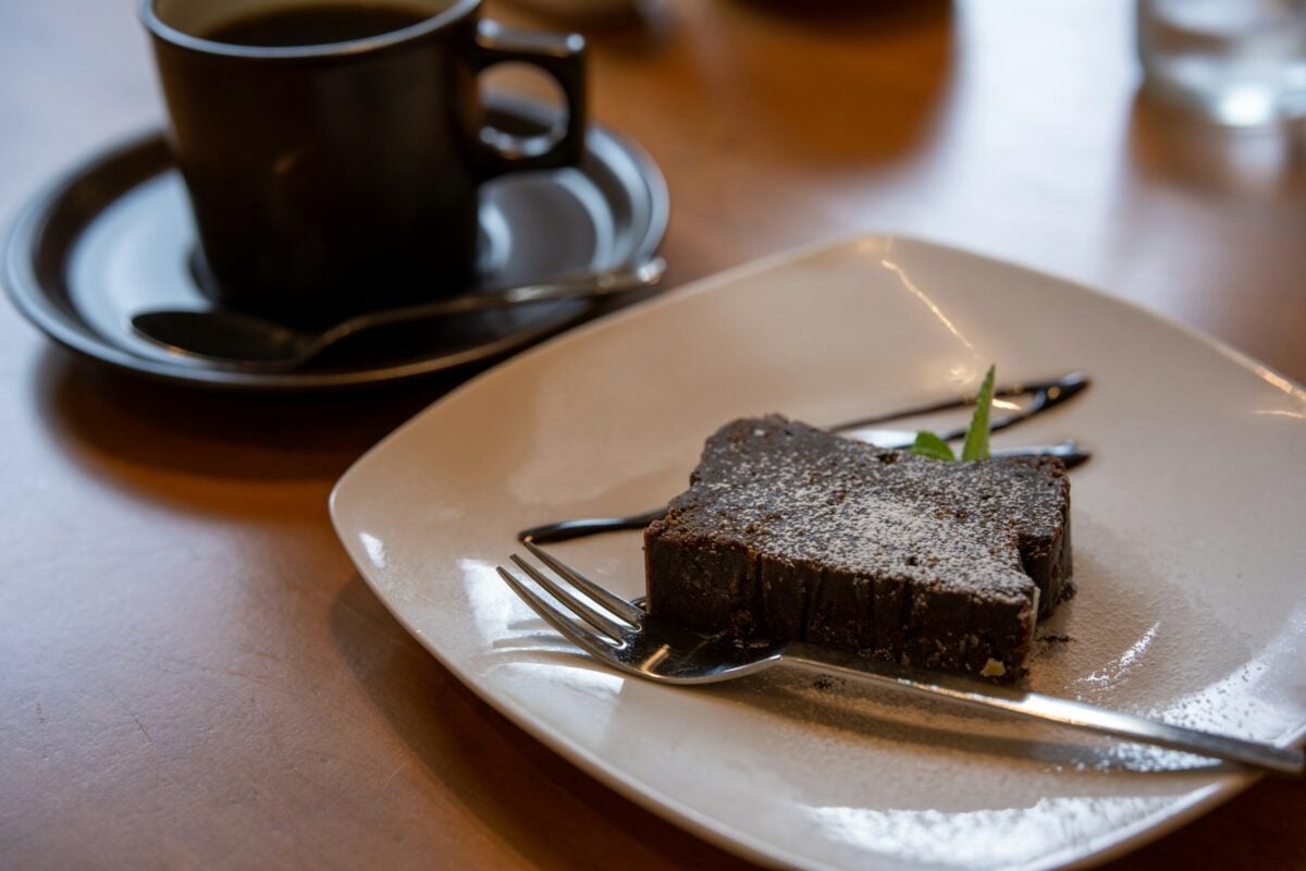 chocolate sheet cake on plate next to cup of espresso