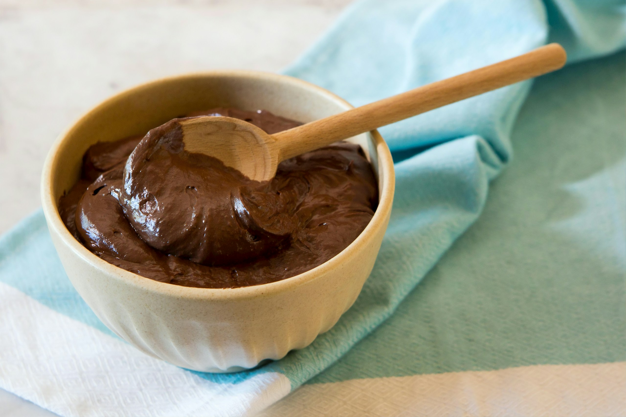 Ganache-Style Frosting in a wooden bowl with a wooden spoon in it