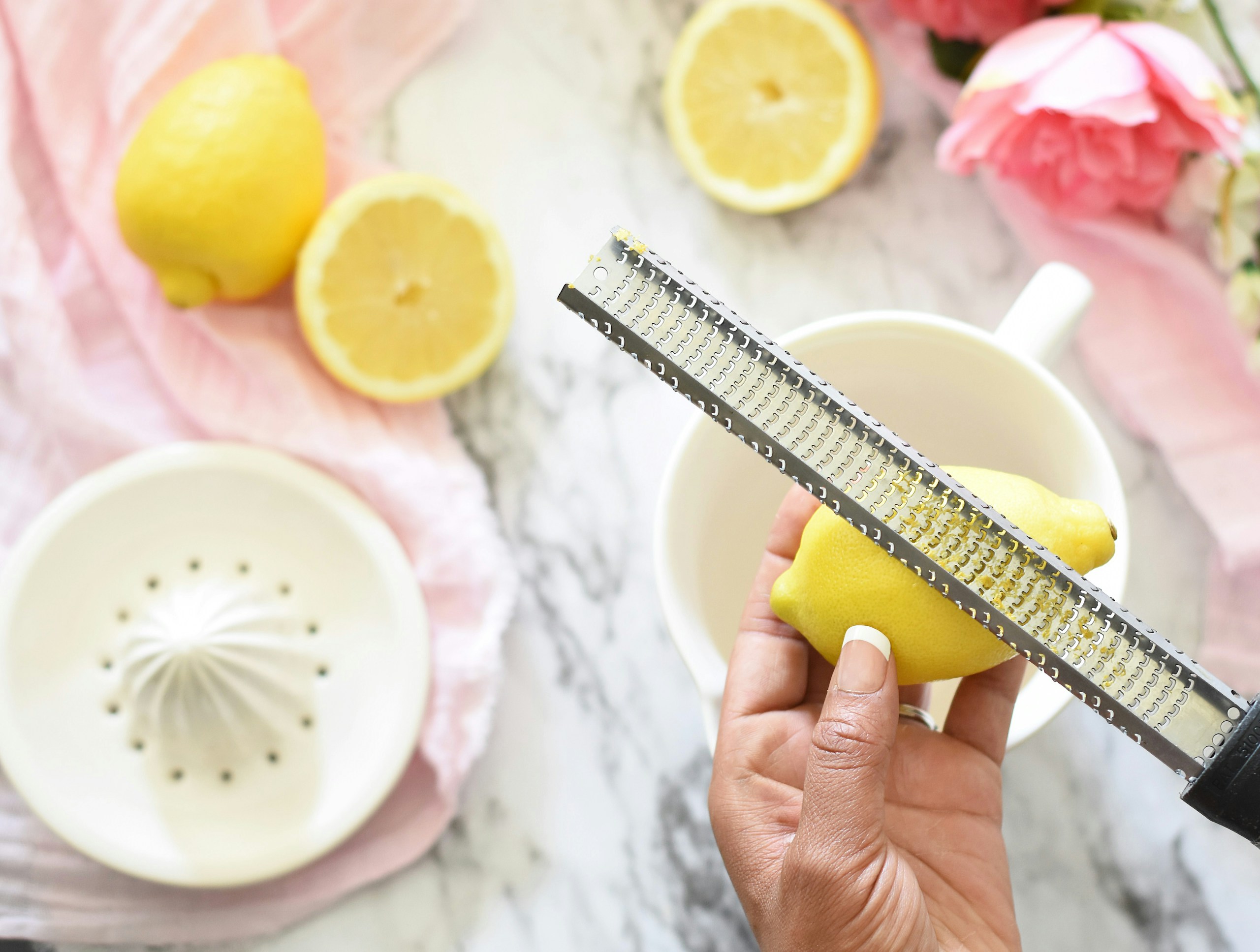 Person zesting a lemon with a grater.