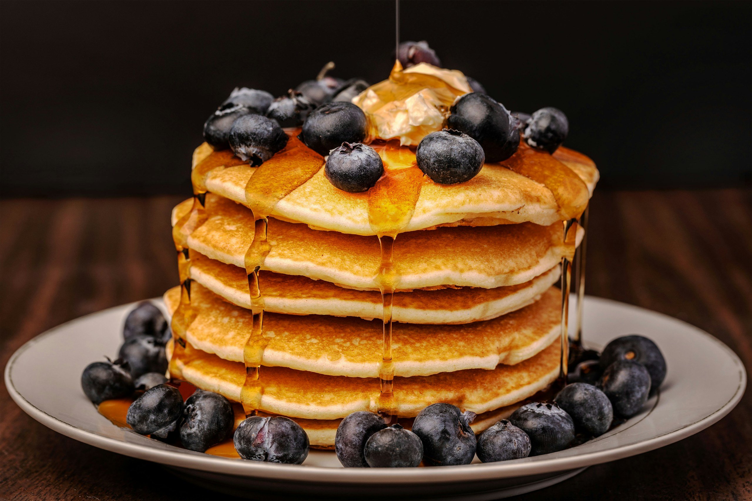 A stack of pancakes covered in blueberries and syrup