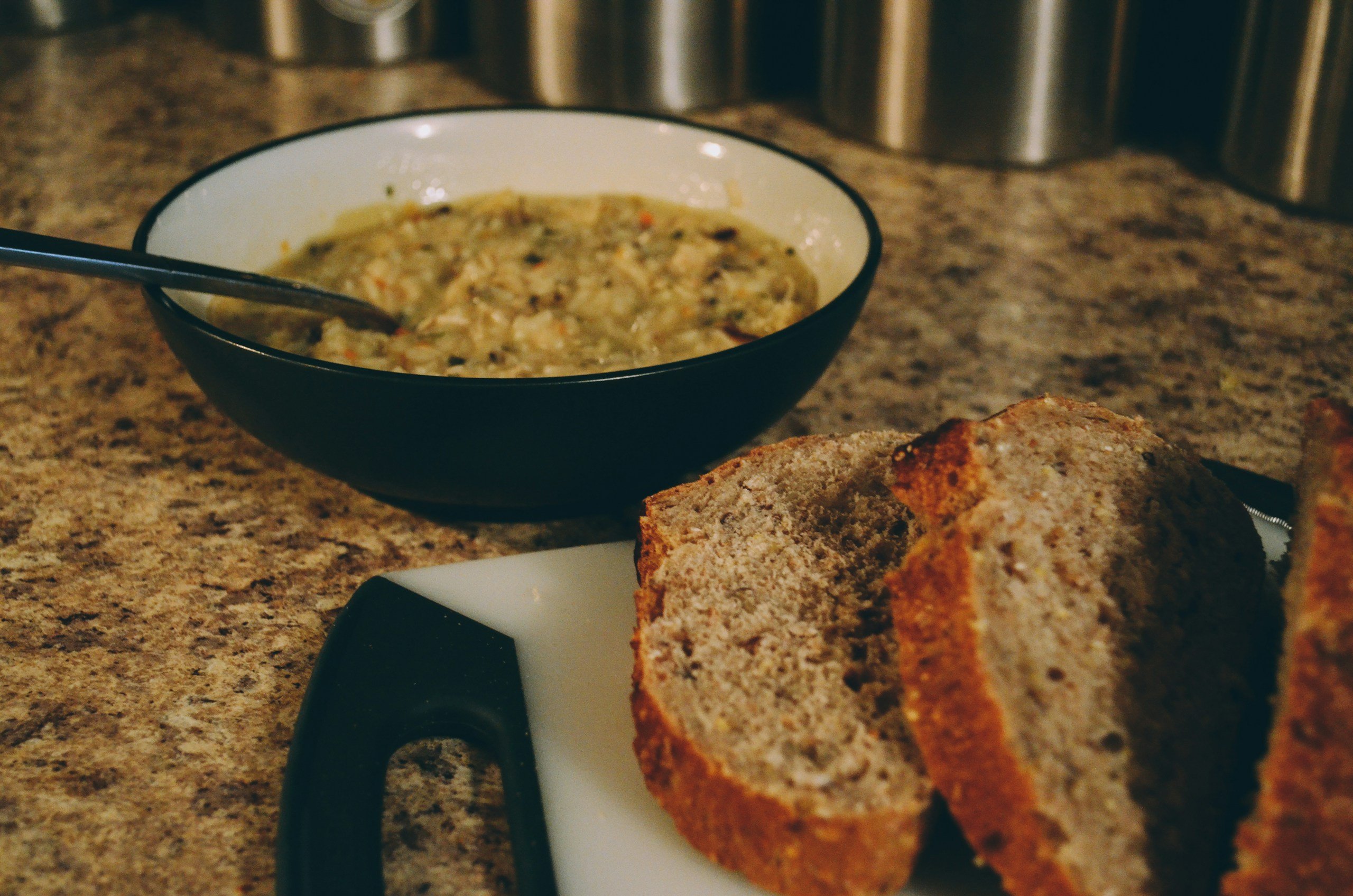 Bread and Soup in a bowl with a spoon.