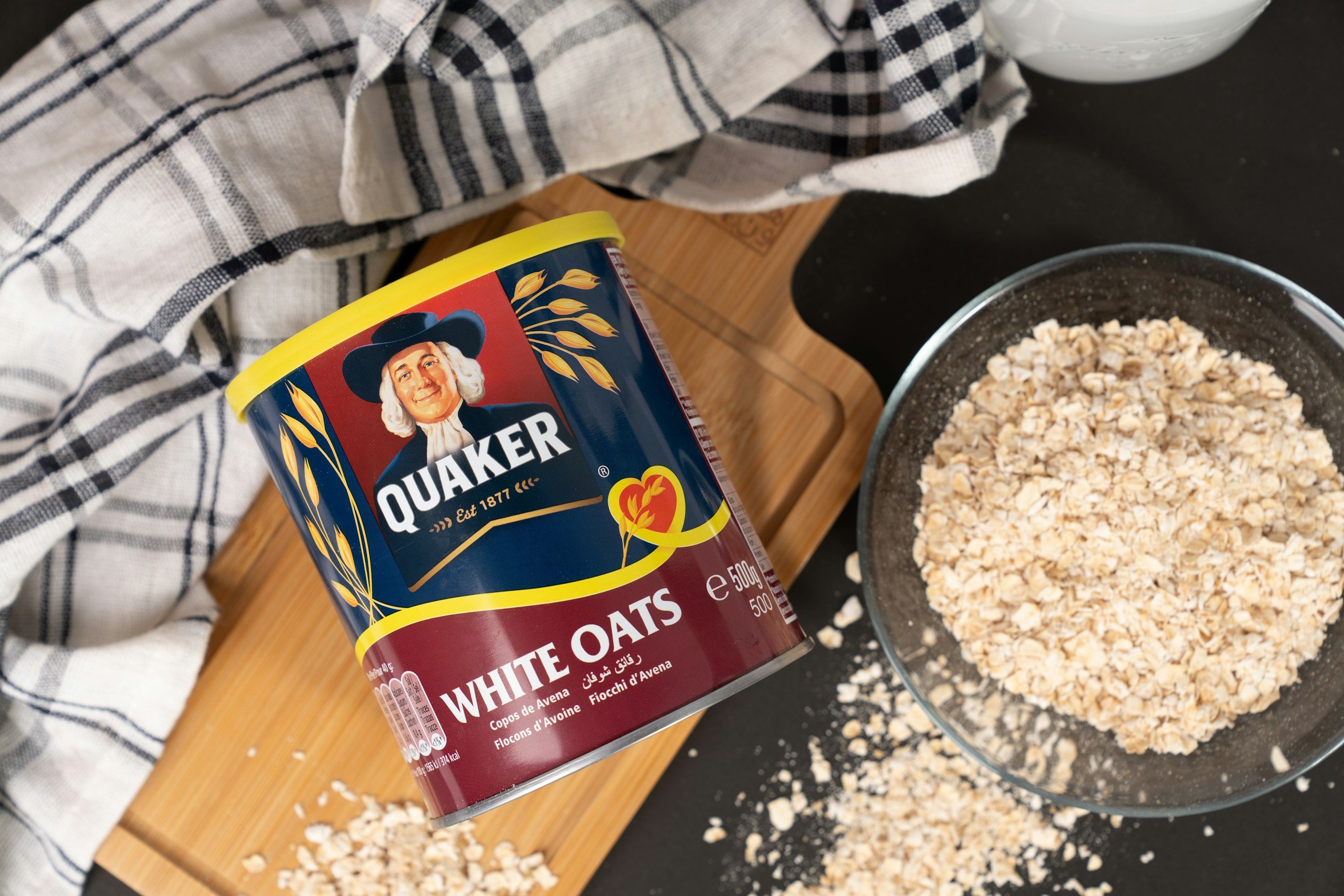Quaker white oat tin beside a glass bowl of oat