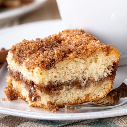 Closeup of a piece of cinnamon crumb cake and coffe cup on a plate